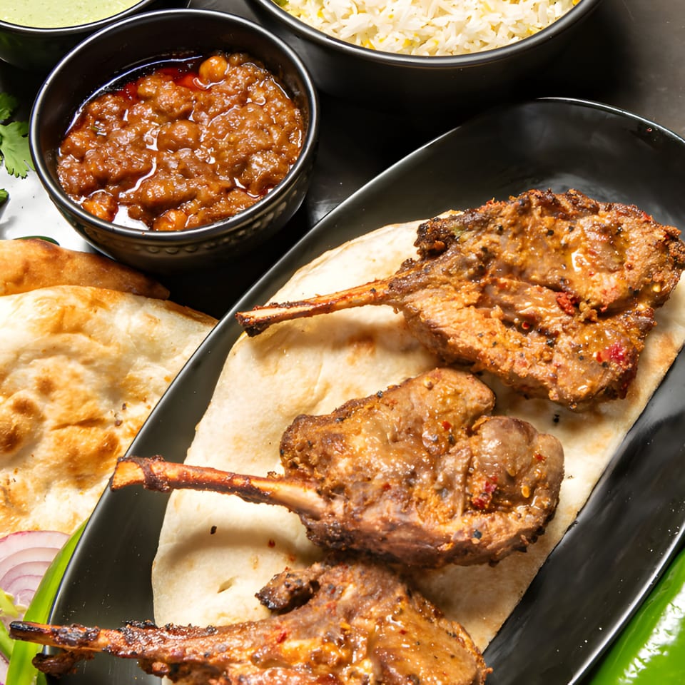 Pakistani lamb chops on naan bread, with chickpea curry, rice, and green chutney.