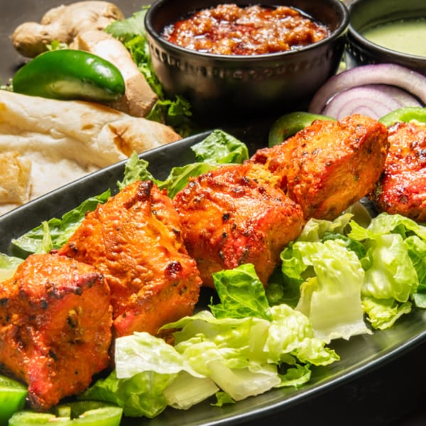 Pakistani chicken tikka with fresh lettuce, naan, sauces, ginger, and jalapeño.