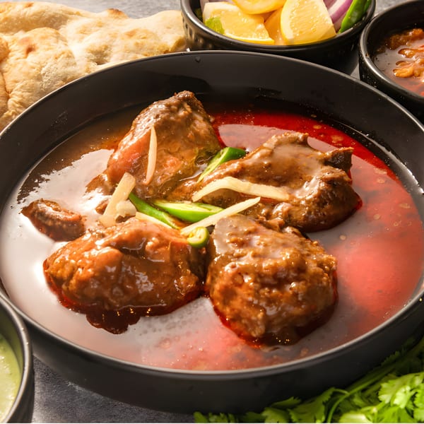 Pakistani Nihari, a rich meat stew, garnished with ginger and green chilies, served with naan.